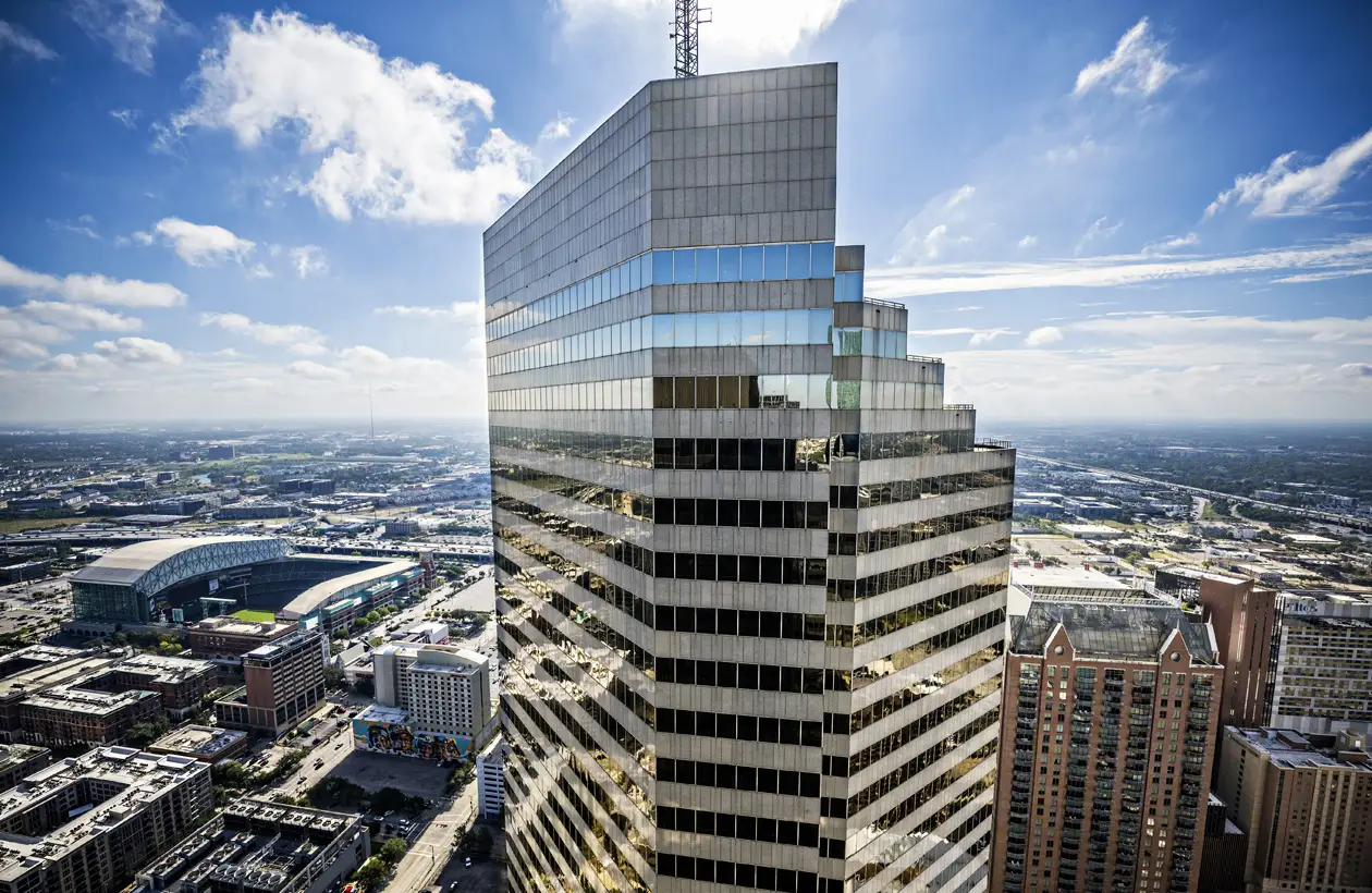 Photo of a tall downtown highrise office building with Daikin Park in the background.