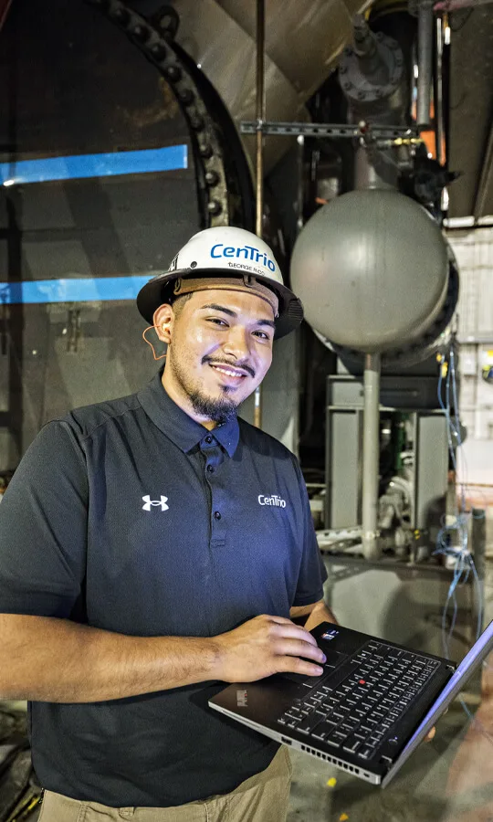 Photo of a CenTrio plant operator posing for the camera with a laptop in their hand.