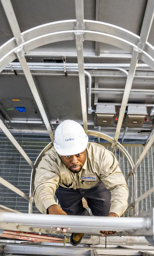 Photo looking down at a CenTrio plant operator who’s climbing up a staircase on site.