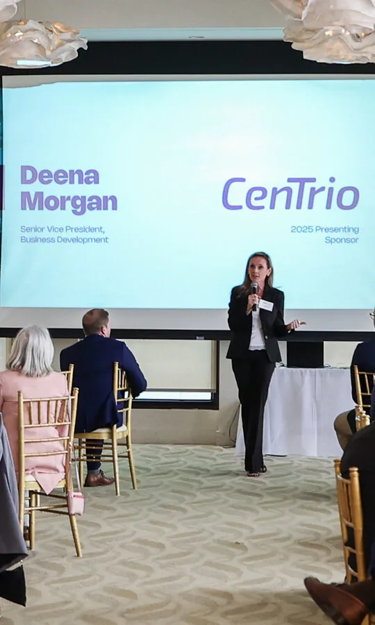 Photo of CenTrio leadership at a speaking engagement addressing a room full of people.