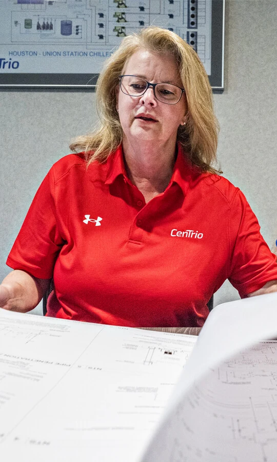 Photo of a Houston CenTrio Plant associate as she reviews schematics spread across a table.