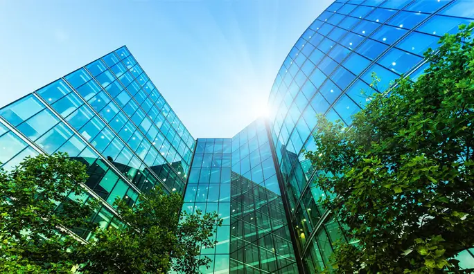 Photo of a building that’s reflecting trees with blue and green tones.