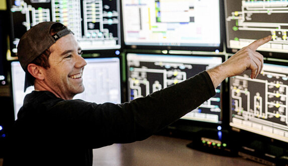 Profile image of one of our Chicago operators pointing at a monitor screen inside our Chicago plant monitoring rooms.