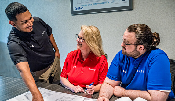 Three CenTrio associates in an office reviewing building blueprints.