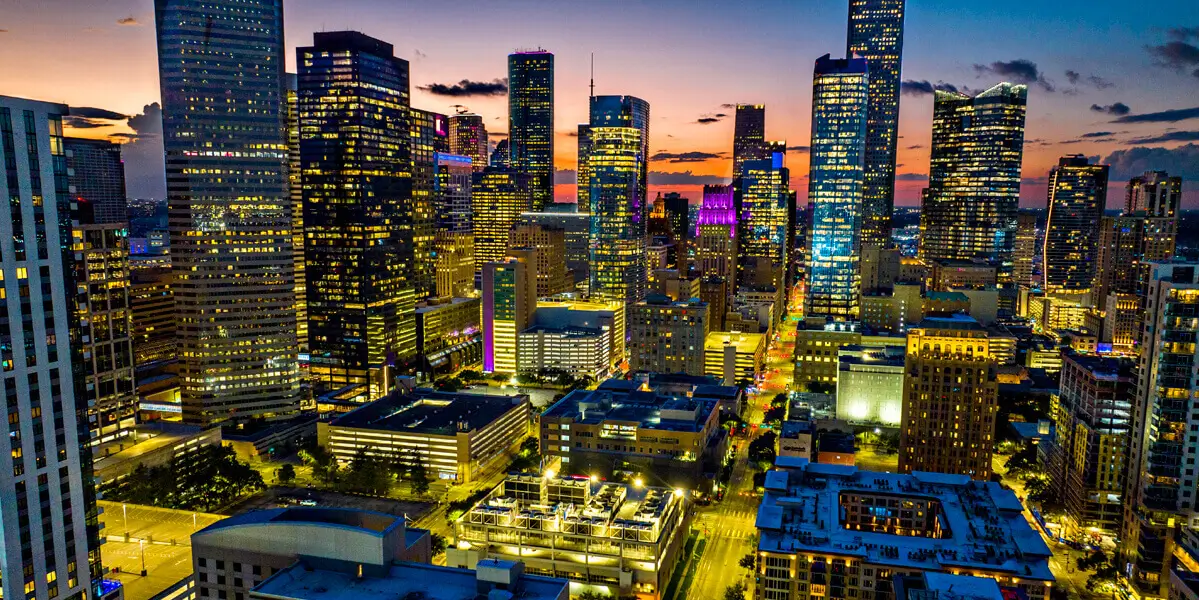 Downtown Houston, TX skyline late during sunset where all the building and city lights are noticeable.