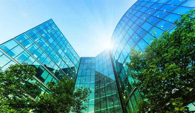 Photo of a building that’s reflecting trees with blue and green tones.