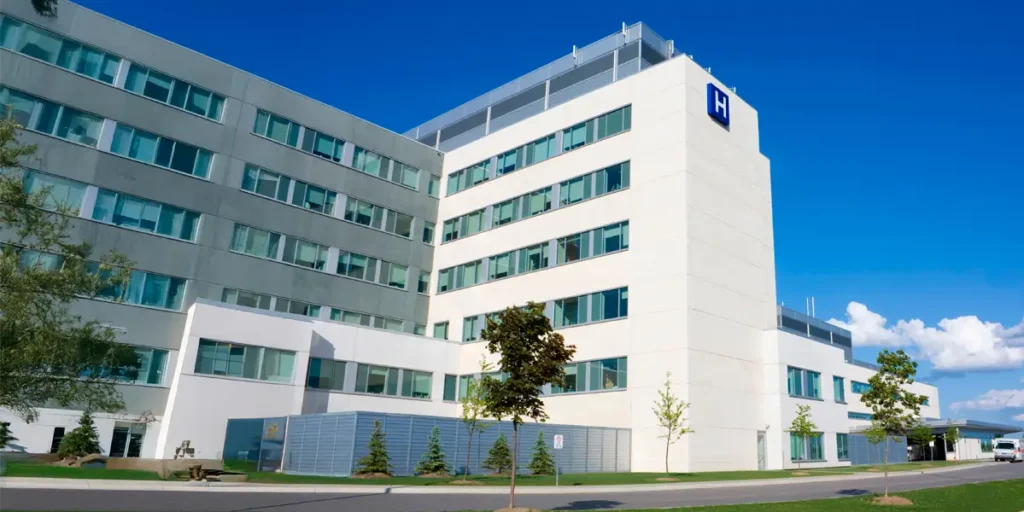Street level view of a generic hospital building in the middle of the day with bright blue sky.