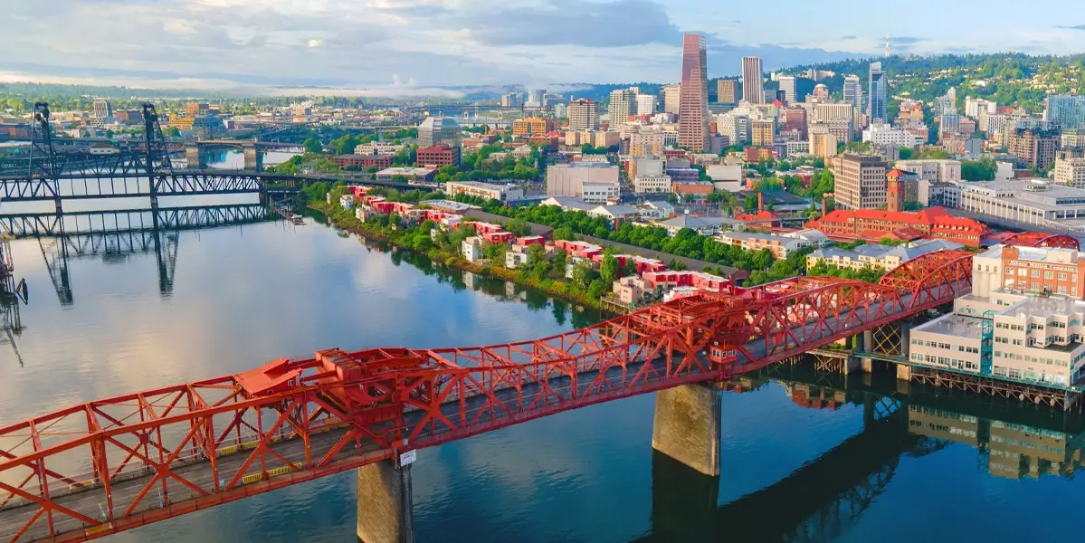 Portland, OR city skyline with the Broadway Bridge and the Willamette River in the foreground.
