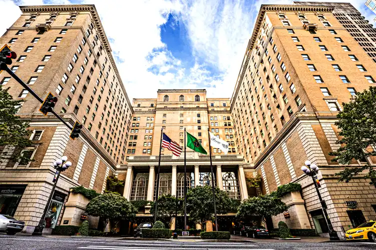 Front entrance to the Fairmont Olympic Hotel in Seattle, WA in the daytime with blue skies and white clouds.