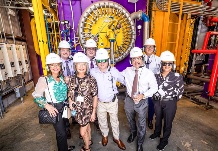 Group of eight people in CenTrio hard hats at our CenTrio LSU plant in front of our new boiler.